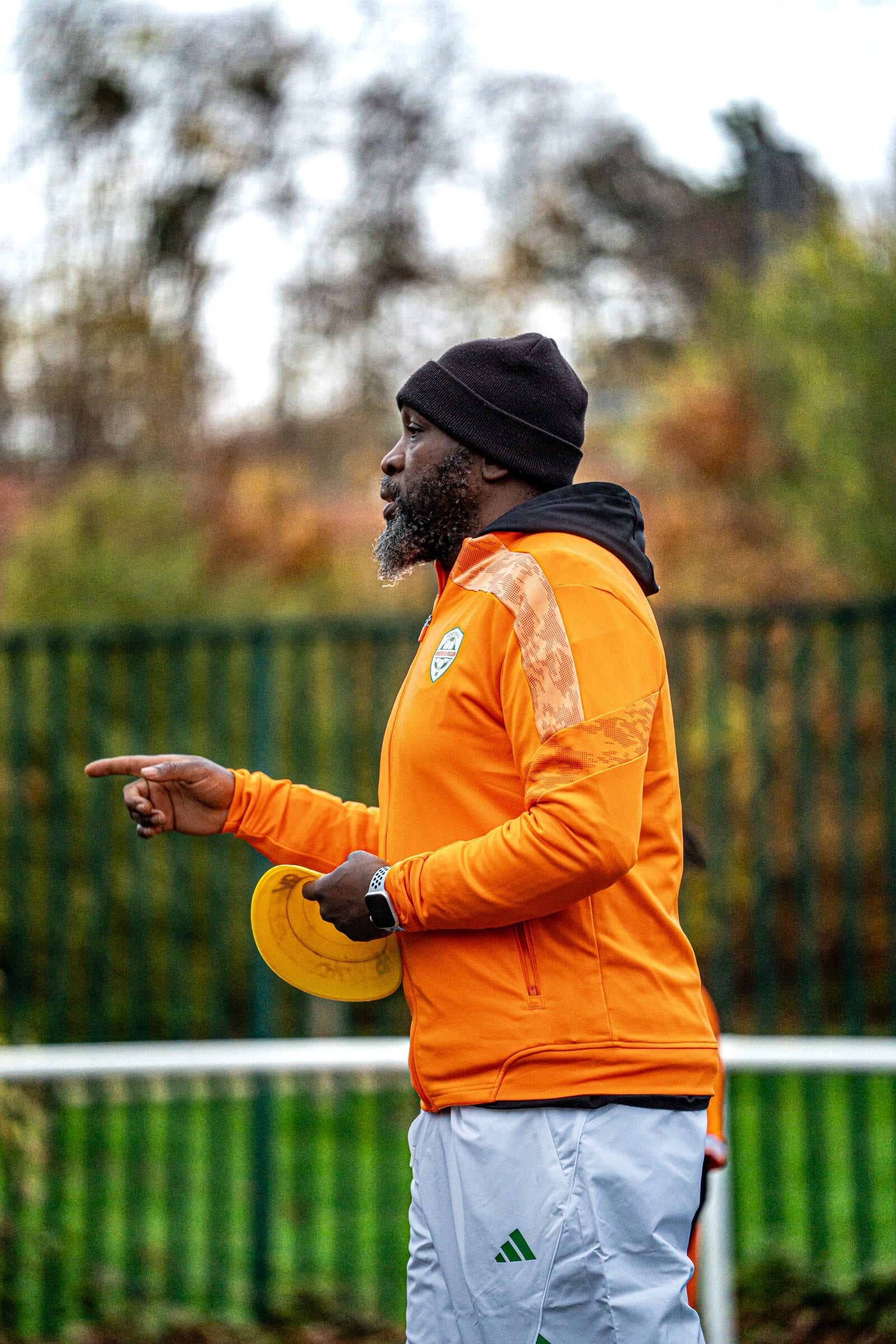 Un éducateur AB Football Académie donne des consignes, plots à la main, sur le terrain